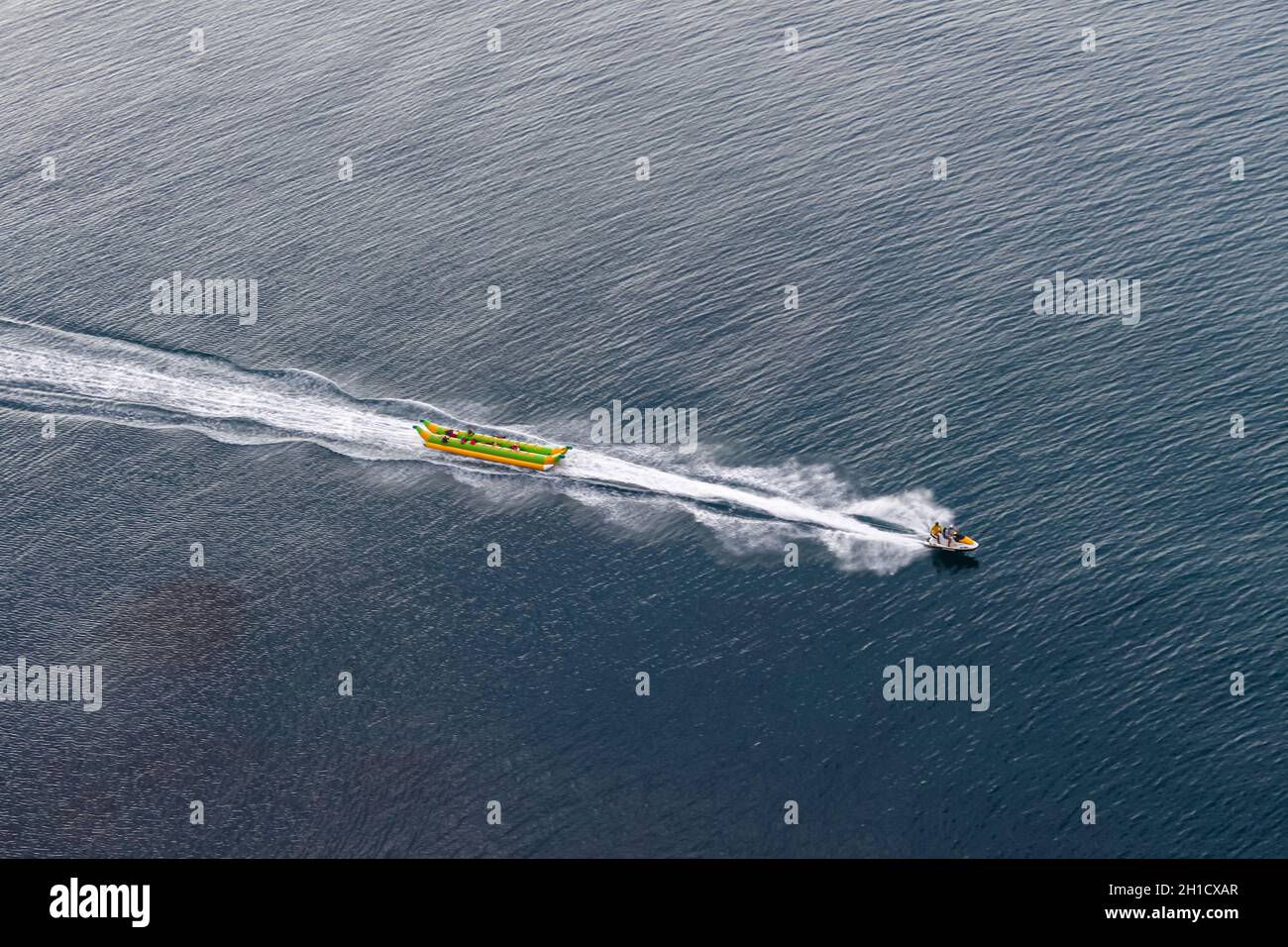 Remorquage de jet ski sur la banane gonflable de la mer.Vue de dessus.Belles ondulations dans l'eau de mer.Une des activités de la station balnéaire Banque D'Images