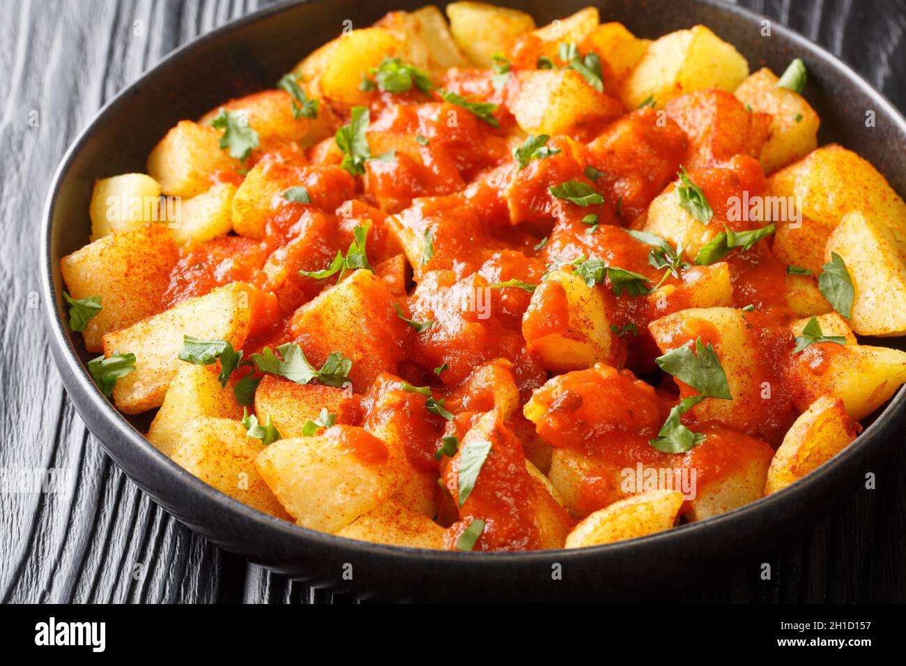 Pommes de terre frites croustillantes espagnoles, servies dans une sauce épicée brava, dans l'assiette de la table.Horizontale Banque D'Images