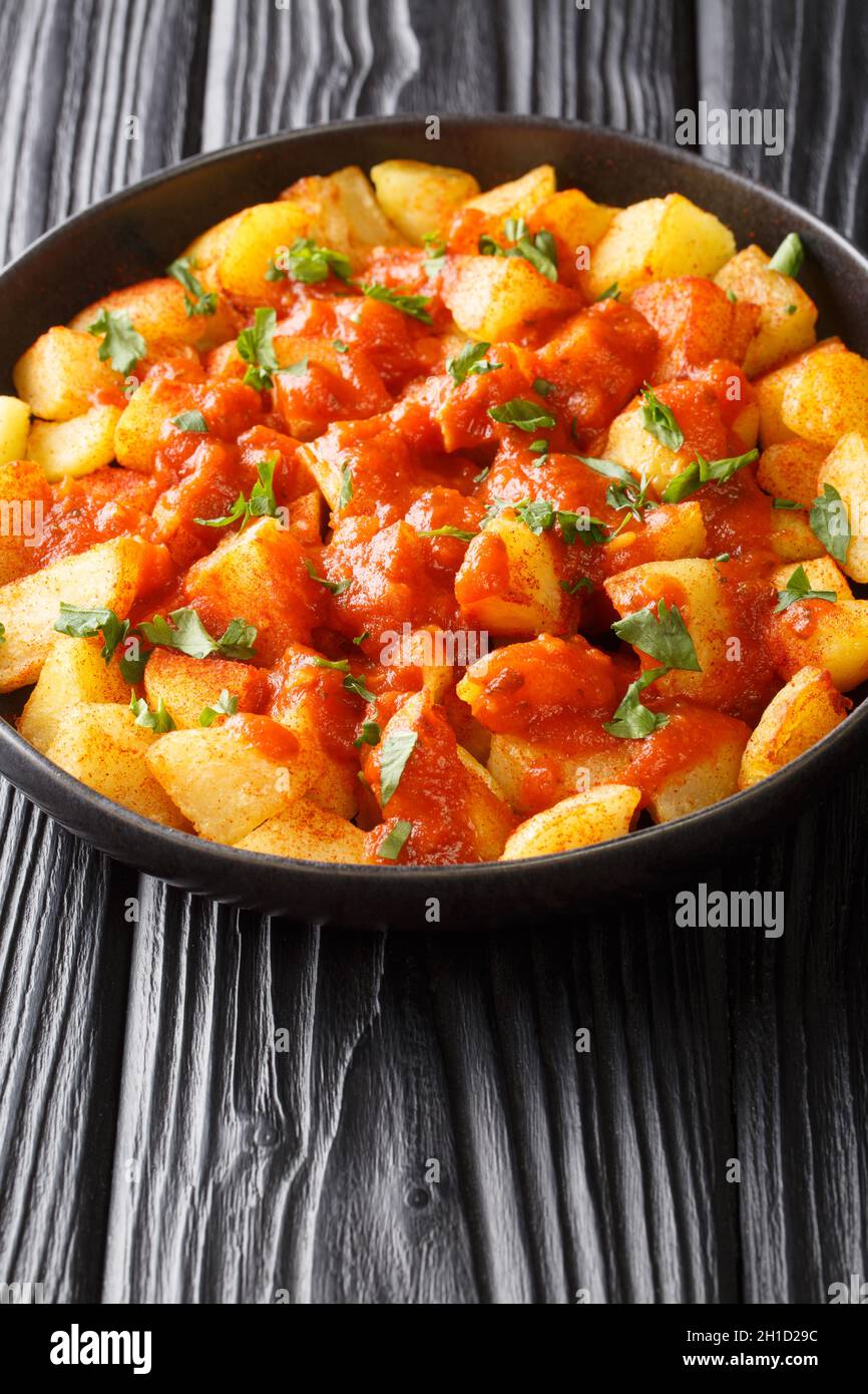 Les patatas Bravas sont des pommes de terre dorées et croustillantes, recouvertes d'une sauce rouge épicée, dans l'assiette de la table.Verticale Banque D'Images