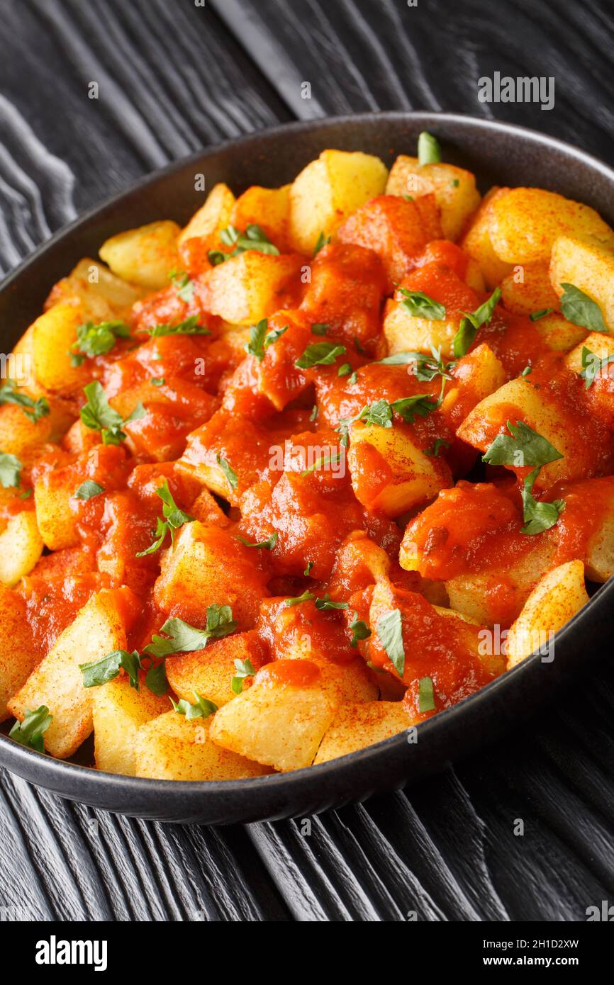 Patatas Bravas est un plat espagnol classique de cubes de pommes de terre frits servi avec une sauce piquante à tremper dans l'assiette sur la table.Verticale Banque D'Images