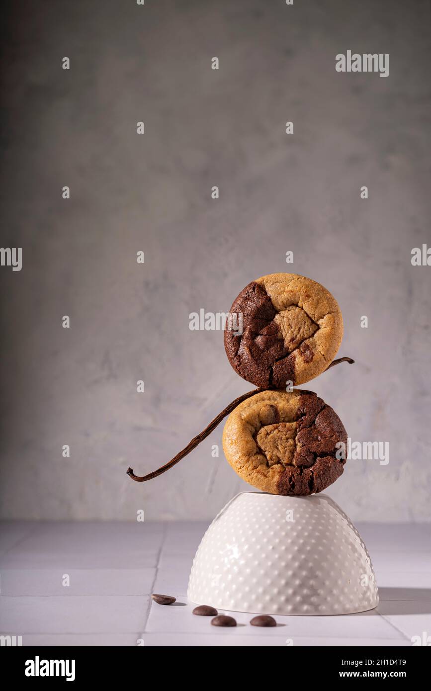 Double biscuits au chocolat et à la vanille sur une pile ludique avec des chips et une gousse de vanille Banque D'Images