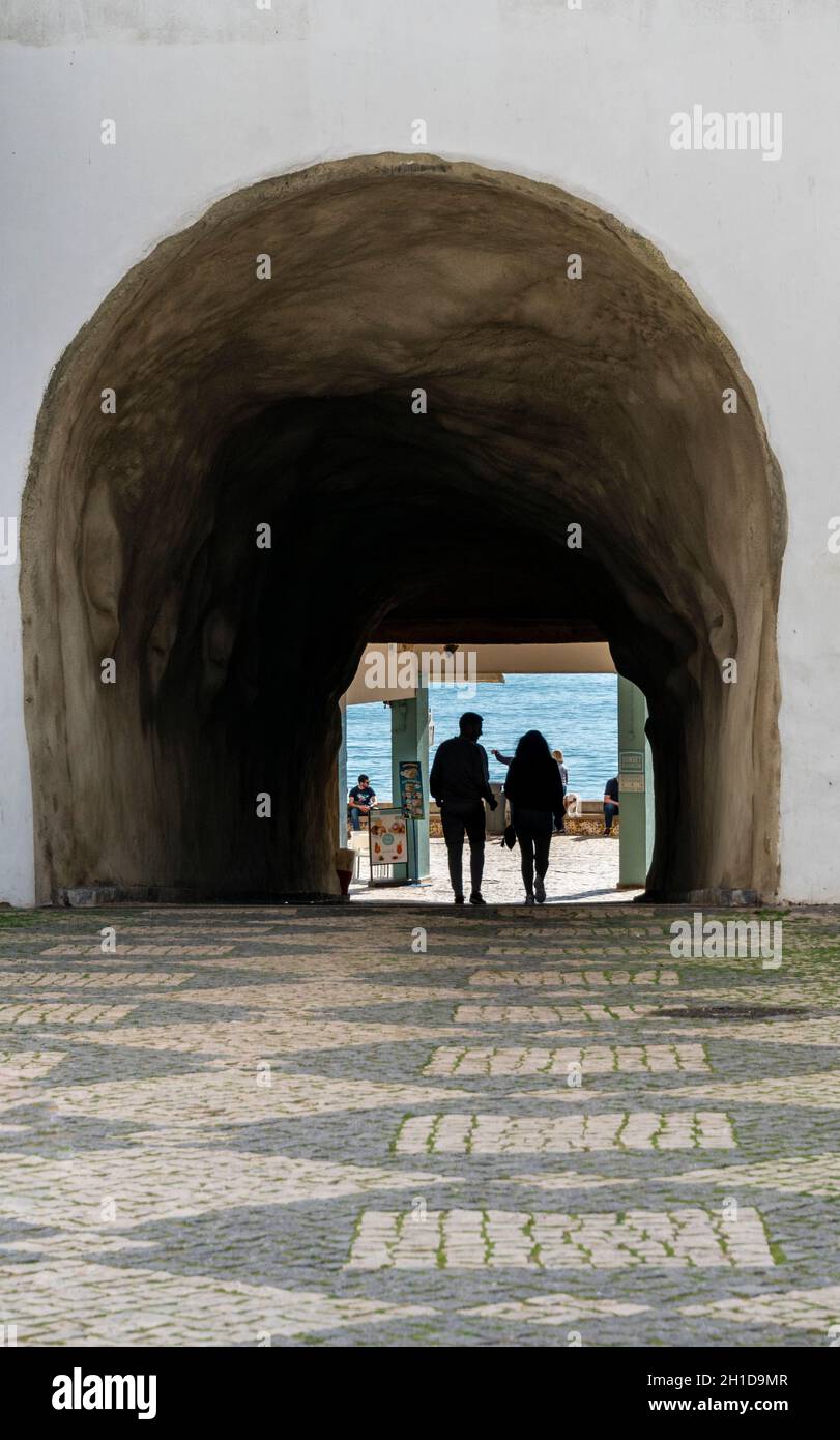 Silhouette d'un couple marchant à travers un tunnel piétonnier à la plage d'Albufeira dans l'Algarve, au Portugal Banque D'Images