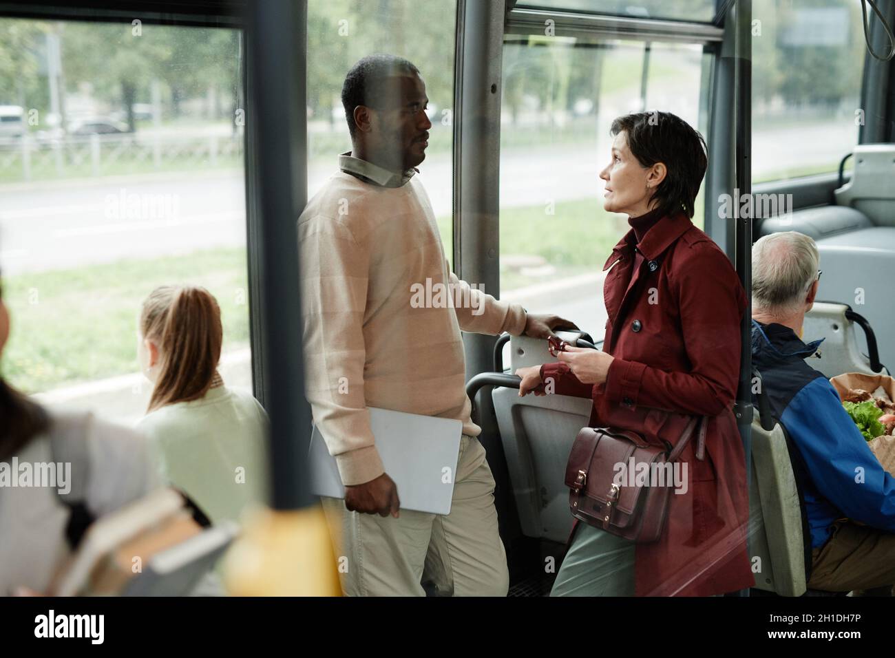 Vue latérale portrait de deux personnes parlant en étant debout dans le bus et en se déplaçant en ville Banque D'Images