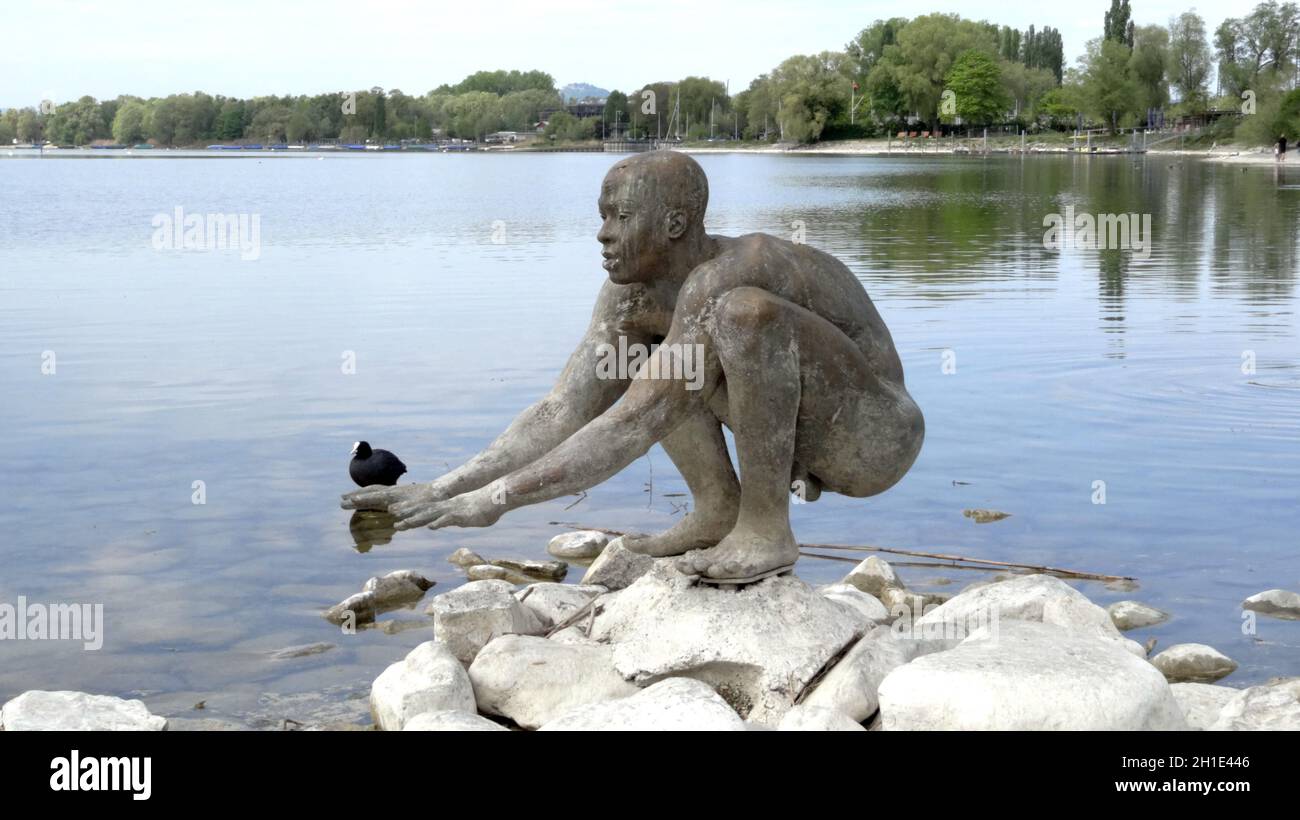Startbereit für die Badesaison scheint die Skulptur am Ufer des Bodensee BEI Radolfzell, an der Hand ist ein Blässhuhn im Wasser des Untersees Themen Banque D'Images
