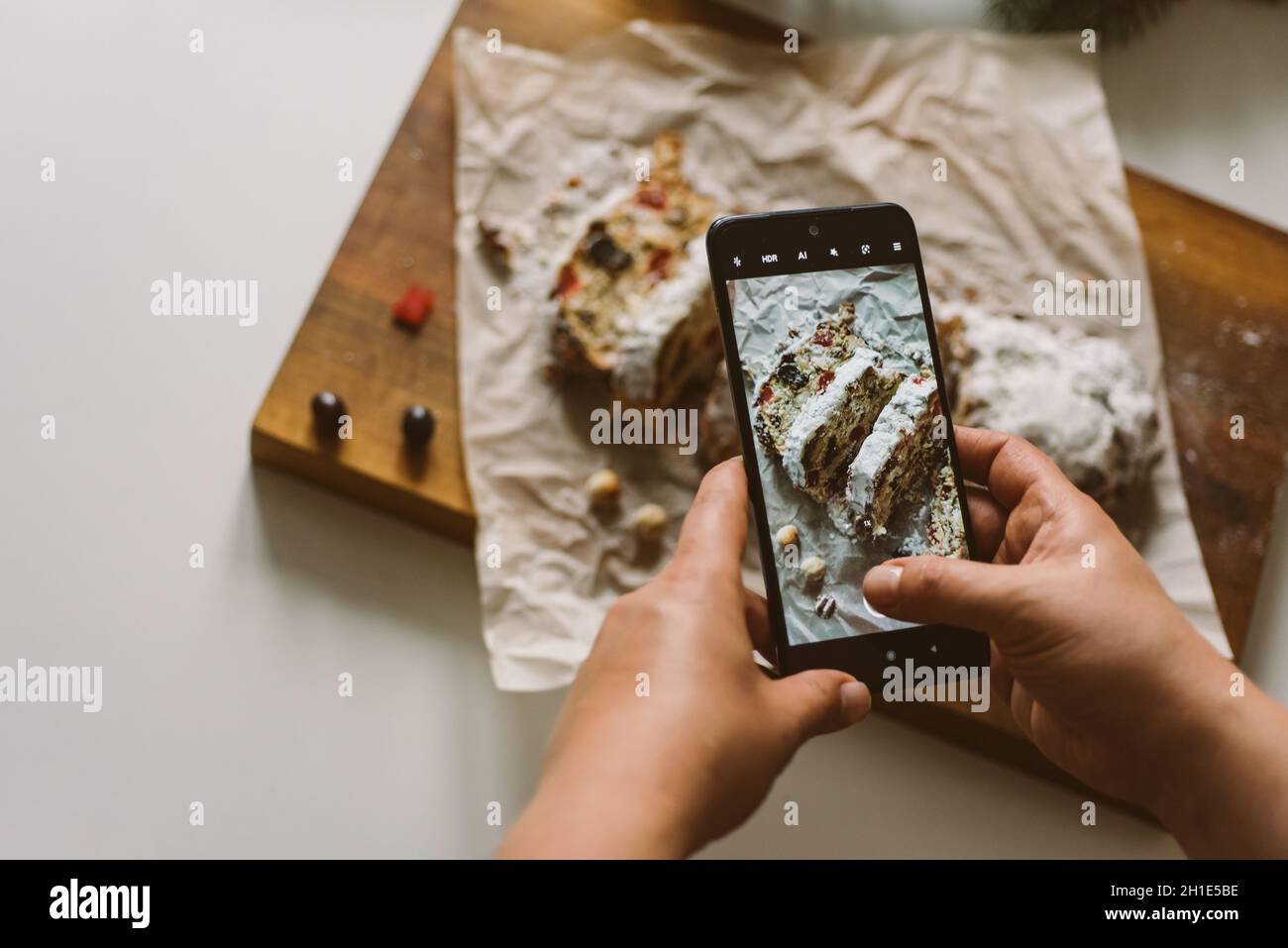 Baker prend une photo du stollen de Noël cuit au four, sur un téléphone portable Banque D'Images