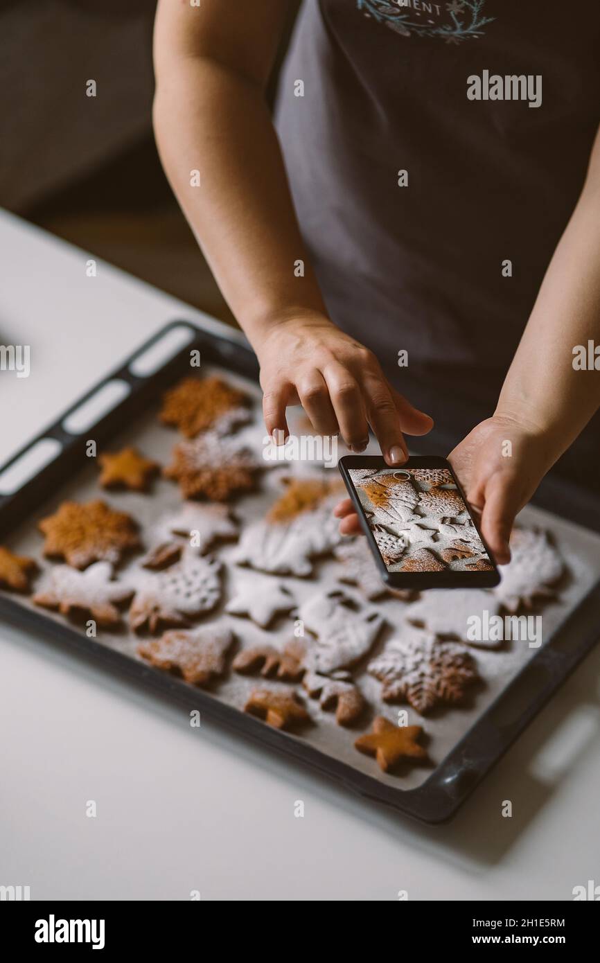 Femme prend des photos sur smartphone pain d'épice de Noël avec du sucre en poudre. Banque D'Images