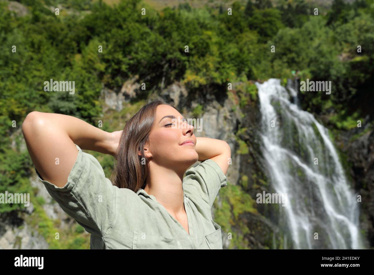 Une femme heureuse respirait de l'air frais et se reposant dans une chute d'eau dans la montagne Banque D'Images