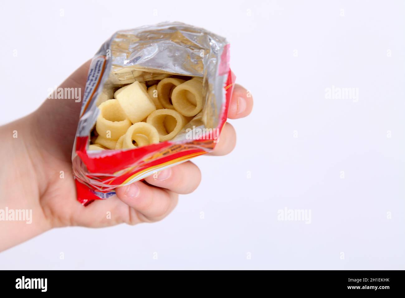 À l'intérieur d'un paquet de Hoops Hula, montrant des chips, dans la main des garçons sur fond blanc Banque D'Images