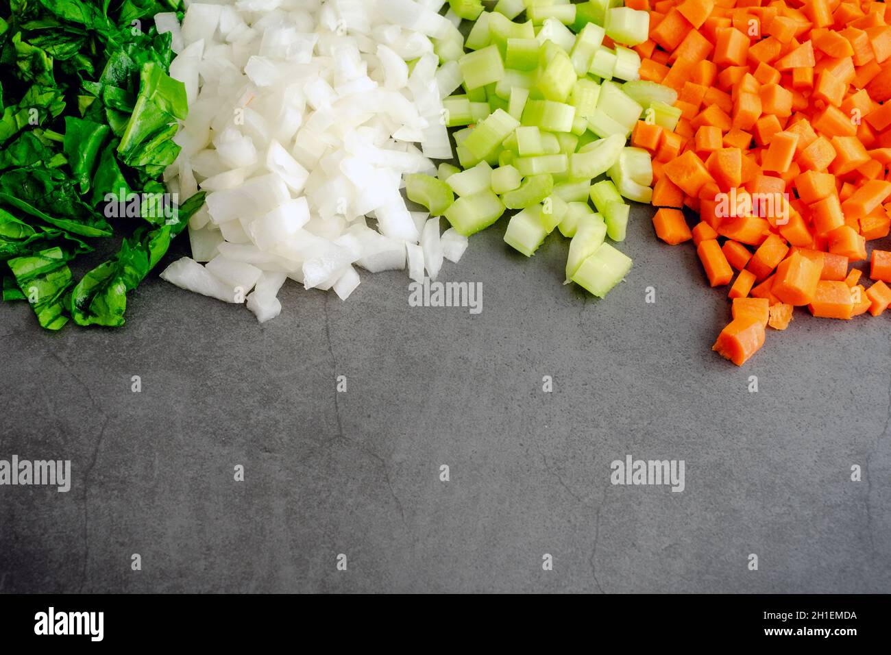 Épinards hachés avec des oignons, du céleri et des carottes en dés : légumes hachés sur fond sombre avec de la place pour la copie Banque D'Images