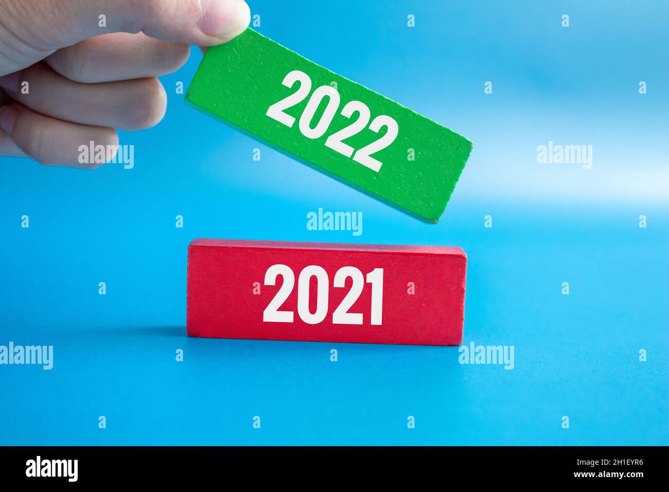 Concept du nouvel an 2022 à venir.Femme met le vert avec 2022 sur le dessus du bloc de bois rouge avec 2021 sur lui.2021 se termine et le nouvel an 2022 commence. Banque D'Images