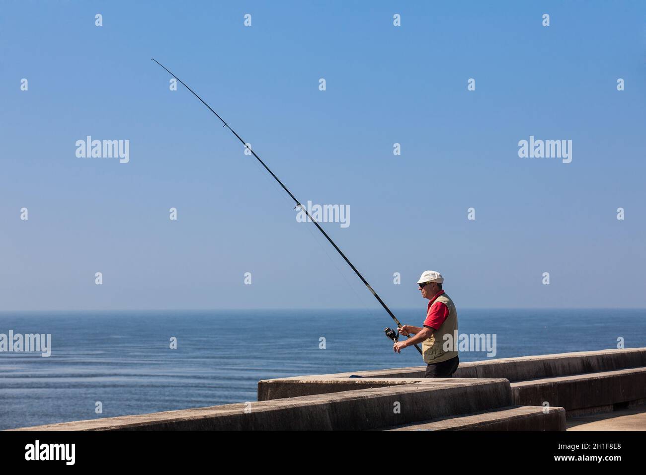 Porto, PORTUGAL - MAI 2018: Homme pêchant sur la magnifique côte de Porto près de l'embouchure du fleuve Douro en début de journée ensoleillée Banque D'Images