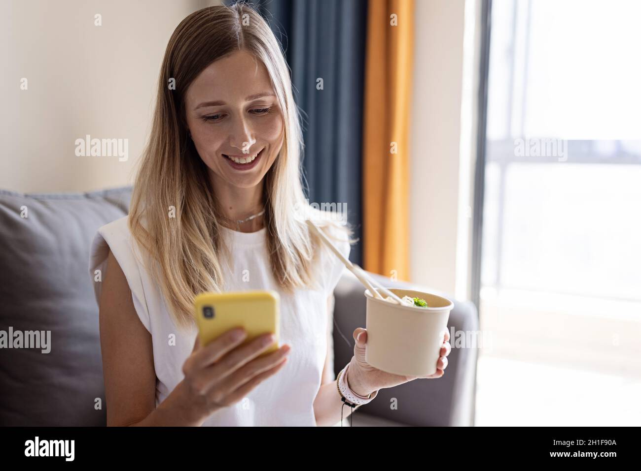 Jeune femme d'affaires caucasienne avec des cheveux blonds portant des vêtements décontractés et a un déjeuner de l'assiette en papier avec des aliments sains pour le bien-être et le régime de céto Banque D'Images