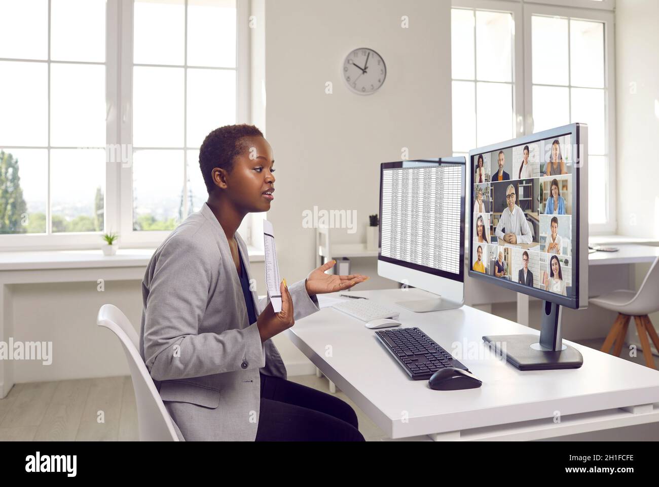 Femme assise devant un ordinateur de bureau et présentant un rapport lors d'une réunion d'affaires en ligne Banque D'Images
