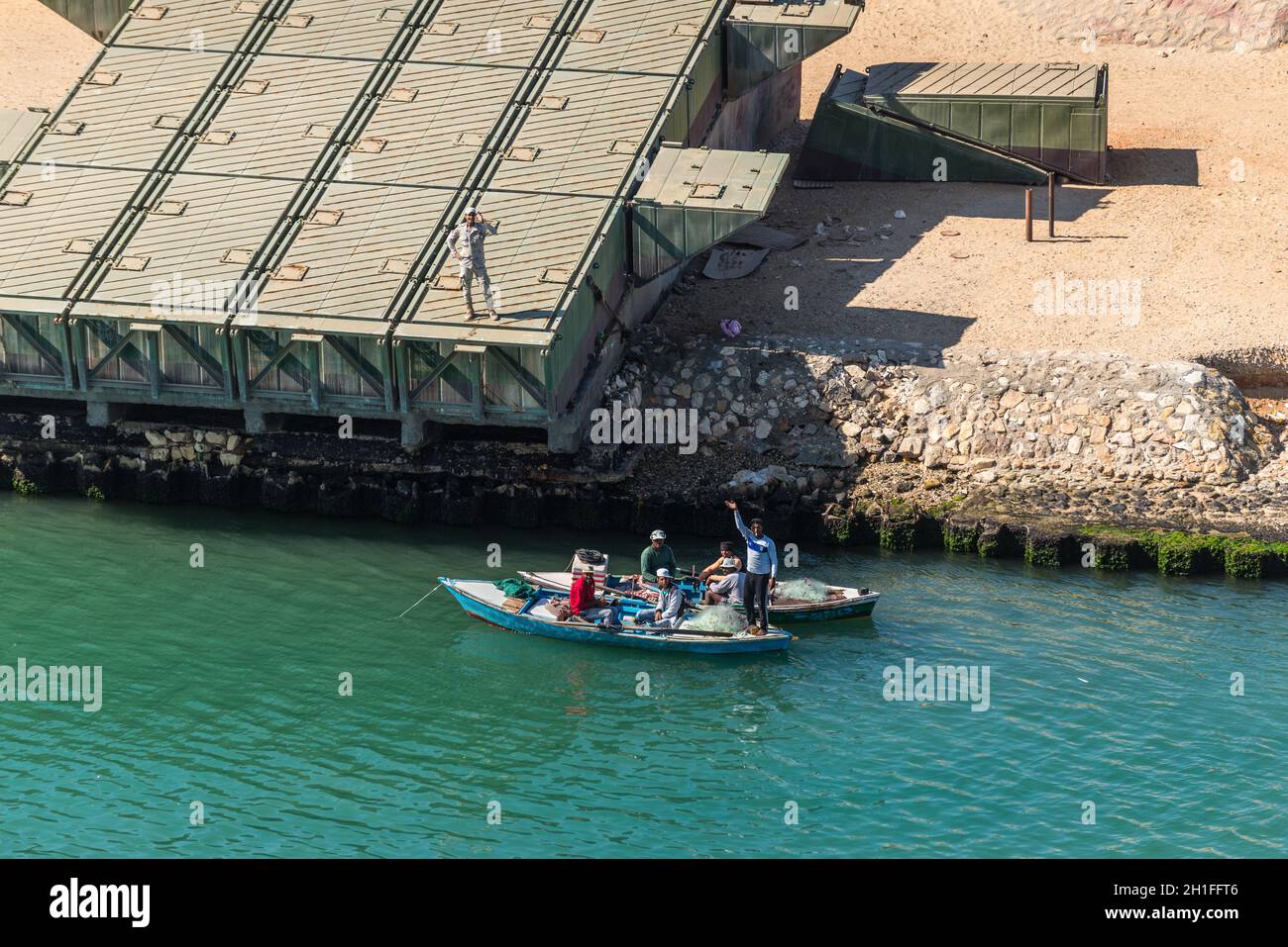 Ismailia, Egypte - Novembre 5, 2017 : les pêcheurs en bateau en bois prendre du poisson sur le net nouveau canal de Suez. Les pontons de pont sur la rive du canal près de Ismailia Banque D'Images