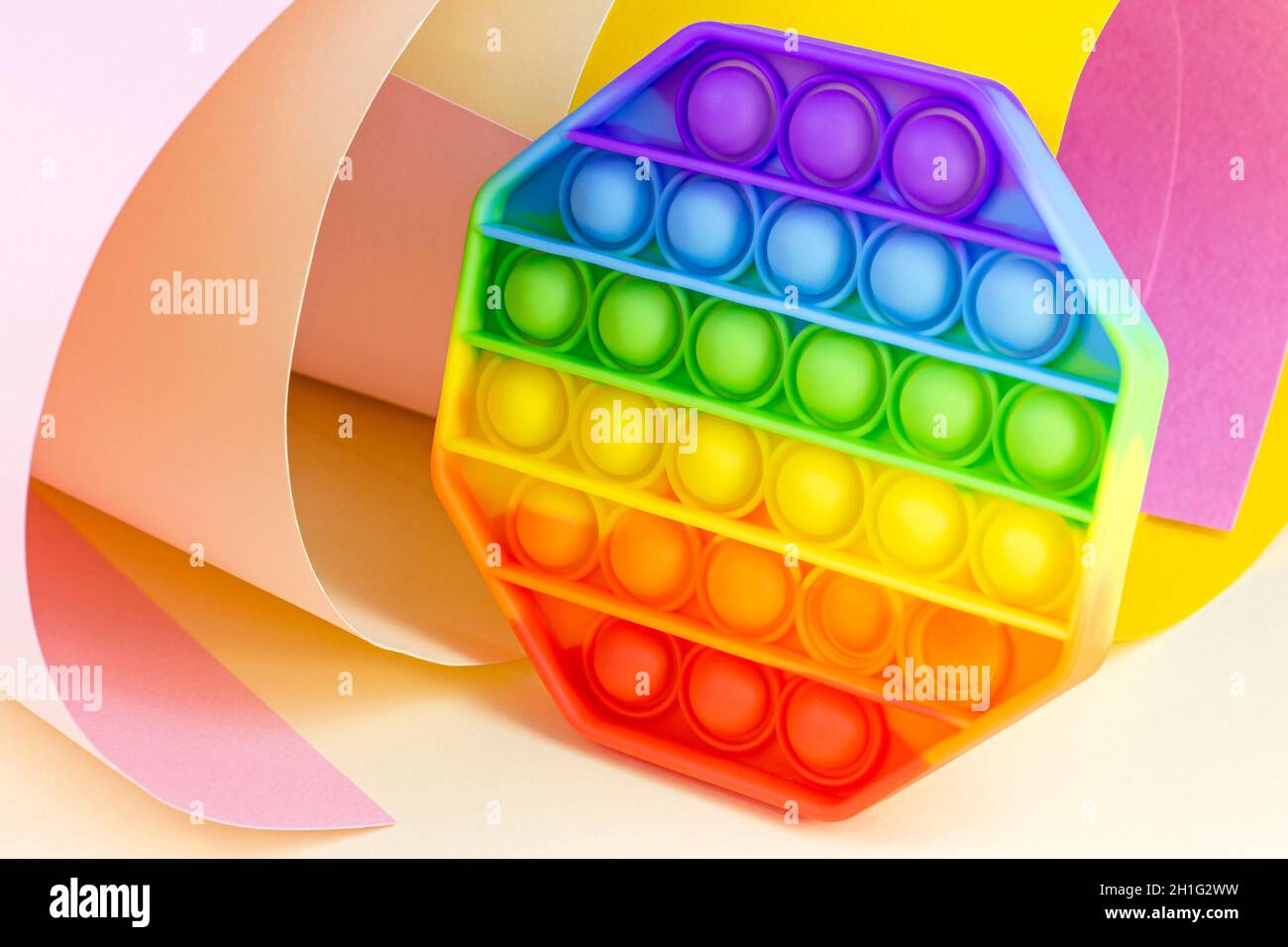 Un jouet sensoriel tendance, simple et bosselé, pour les enfants sur fond de papier brillant.Populaire antistress silicone enfants bulle de couleurs arc-en-ciel. Banque D'Images