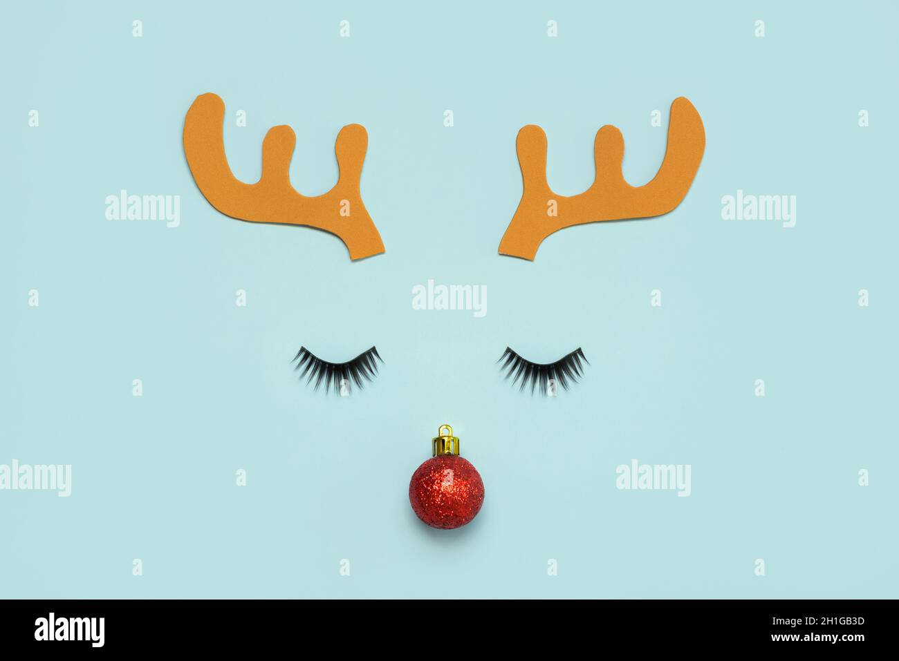 Joyeux Noël.Noël Rudolph renne cornes avec faux cils et boule de noël rouge sur fond bleu.fond de concept de Noël Banque D'Images