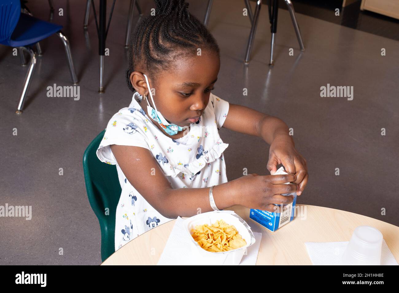 Éducation préscolaire 4-5 ans repas heure petit déjeuner fille ouverture propre réservoir de lait Banque D'Images