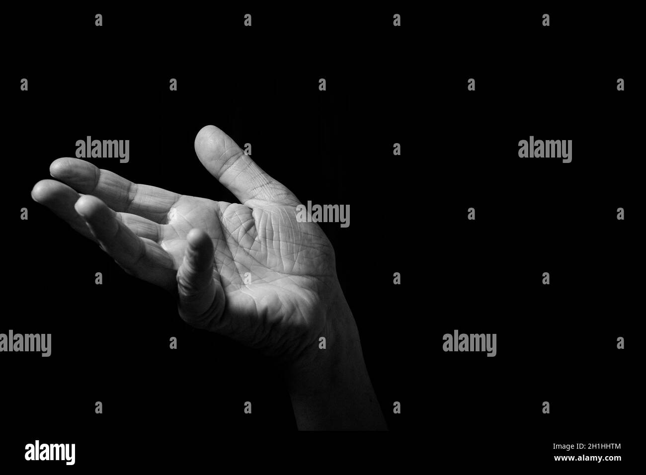 Image en noir et blanc d'un homme froissé tenant des gestes avec paume ouverte, isolée sur un fond noir avec un éclairage spectaculaire. Banque D'Images