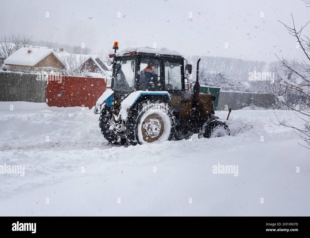 En cas de forte chute de neige, le tracteur se dégage de la route enneigée. Banque D'Images