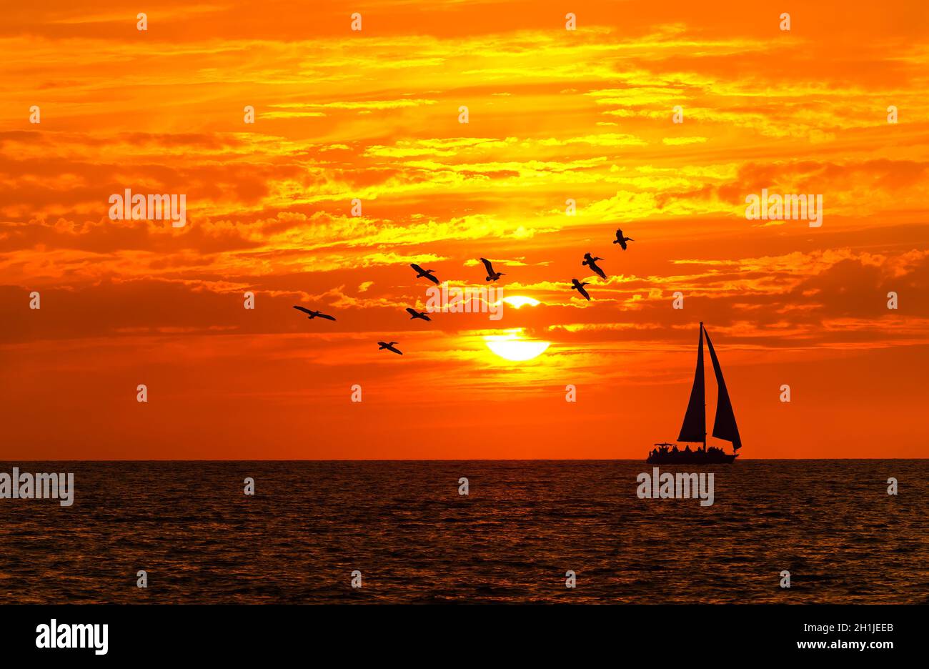 Un Voilier est la voile le long de l'océan avec Un coucher de soleil coloré sur l'océan Horizon Banque D'Images