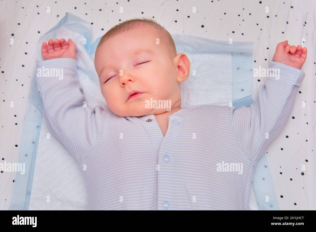 Le bébé dort dans une posture en forme d'étoile avec ses bras écartées sur  un lit d'enfant.Enfant de trois mois Photo Stock - Alamy