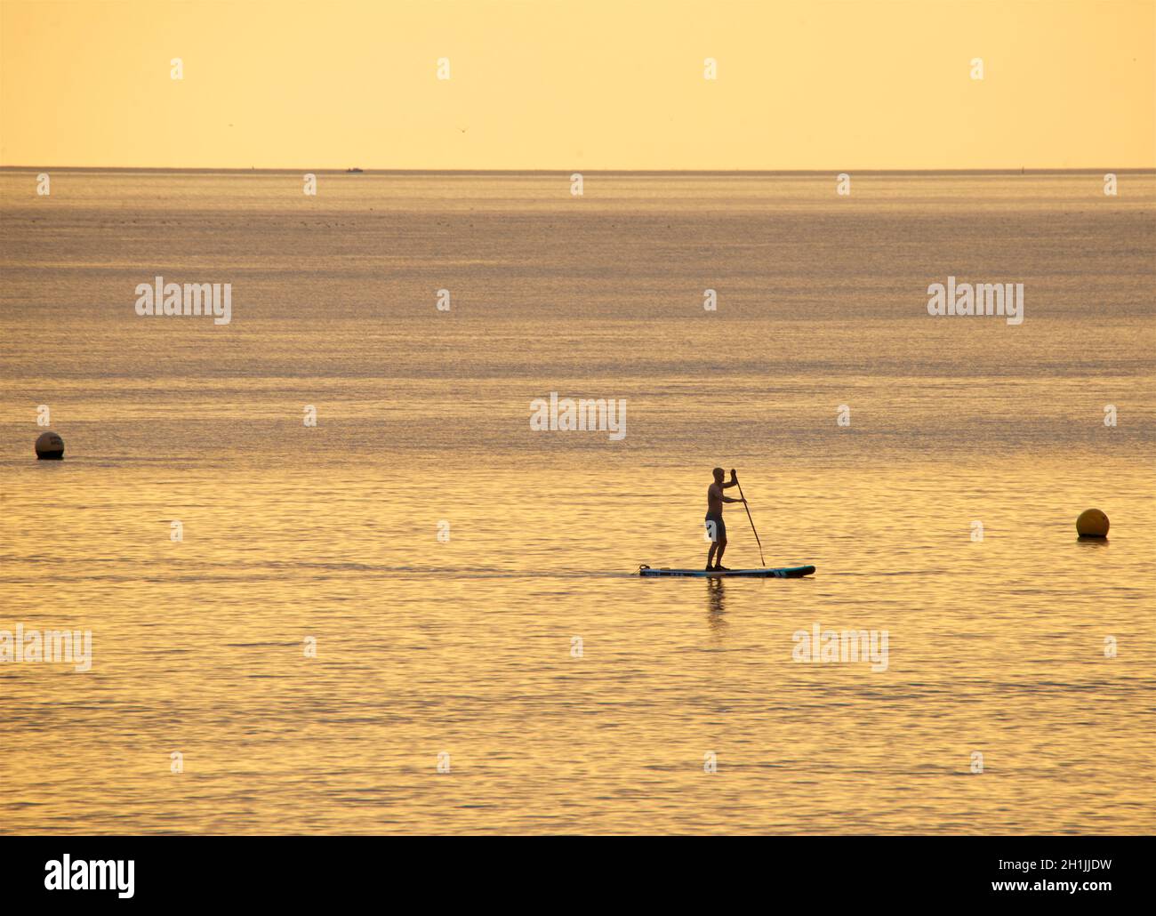 Paddleboarder silhouetted paddleboard d'une plage de Hove au coucher du soleil.Brighton & Hove, Englod, Royaume-Uni Banque D'Images