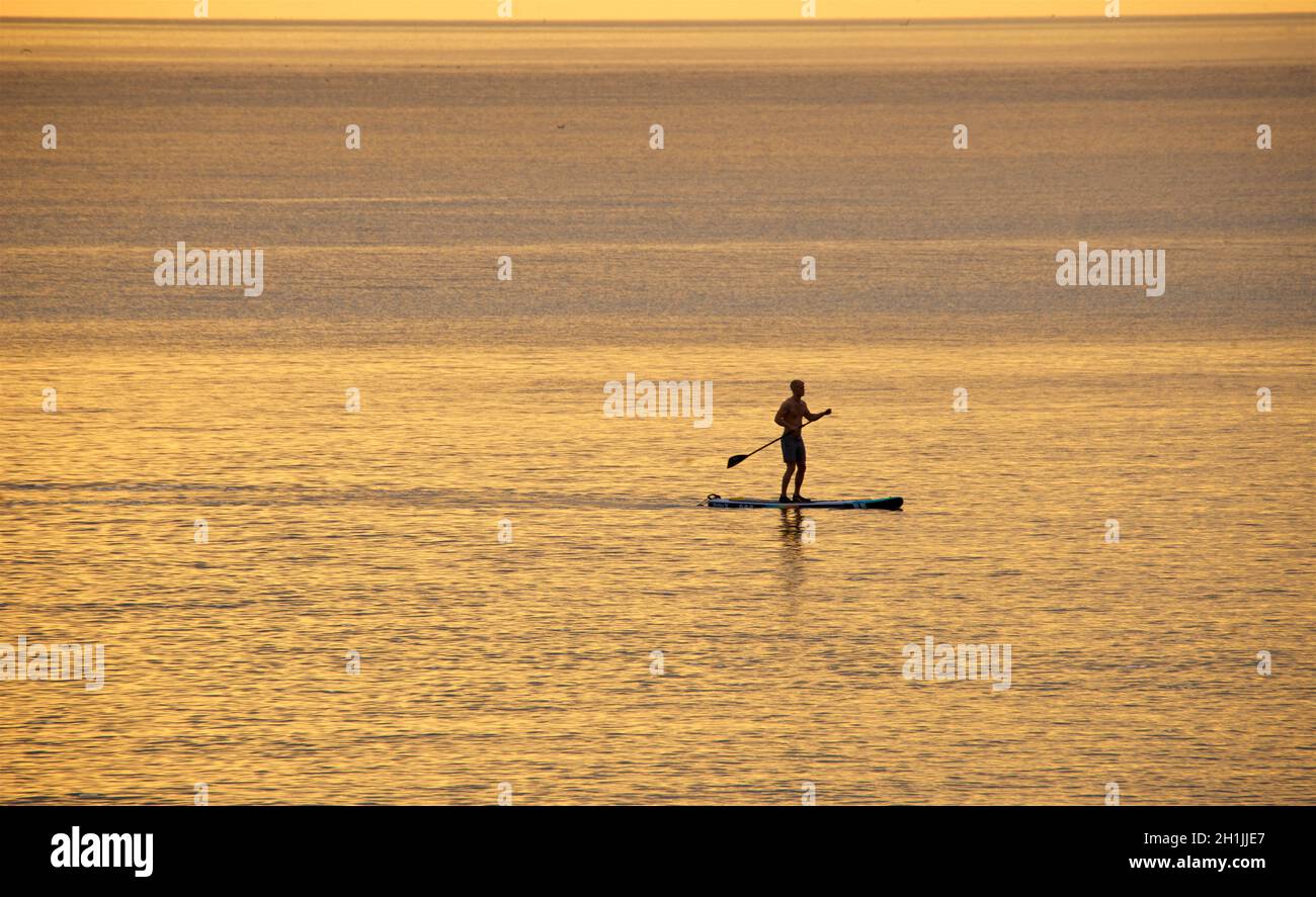 Paddleboarder silhouetted paddleboard d'une plage de Hove au coucher du soleil.Brighton & Hove, Englod, Royaume-Uni Banque D'Images