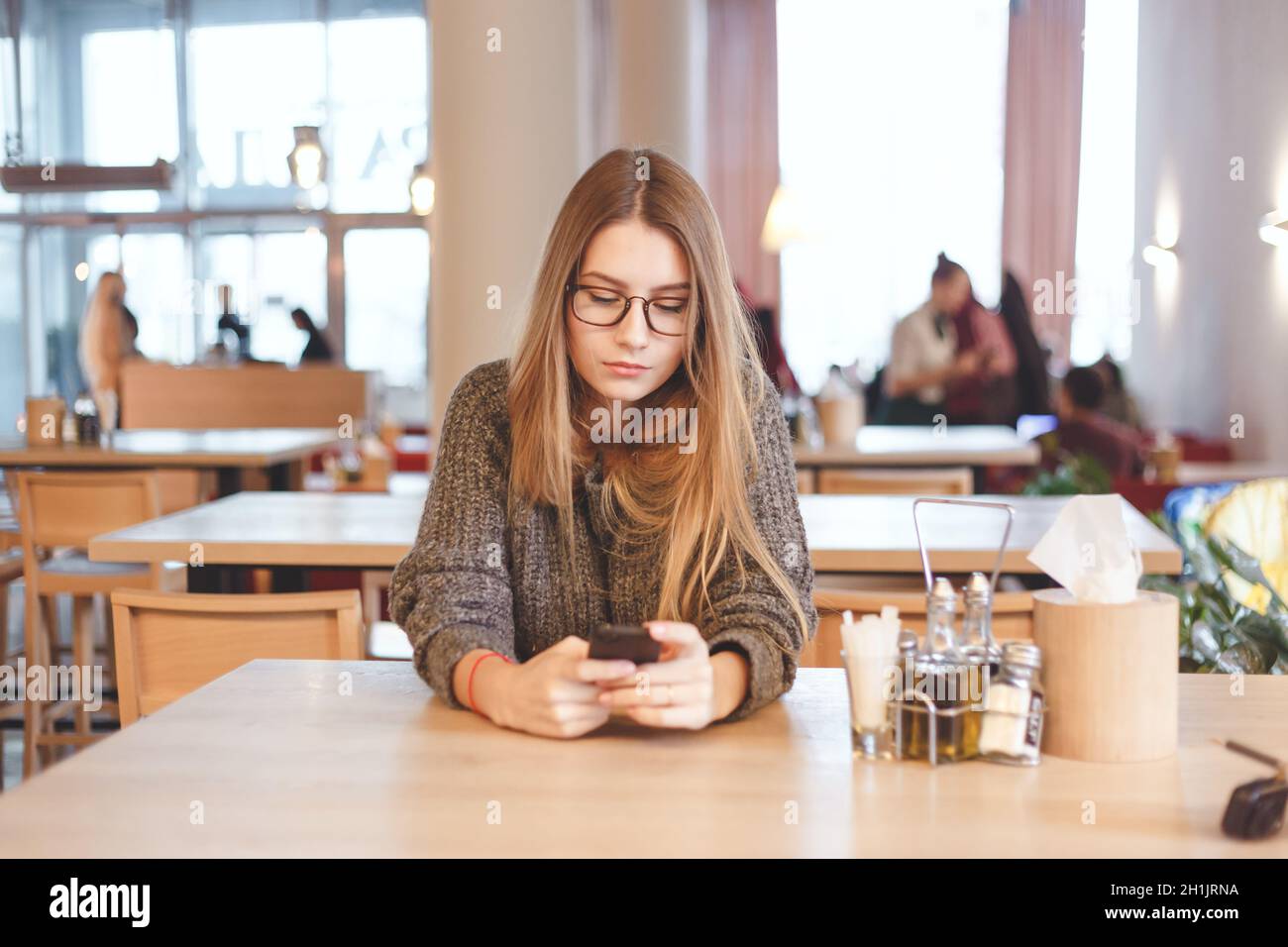 Charmante femme avec un beau sourire de lire de bonnes nouvelles sur téléphone mobile au repos dans la région de coffee shop Banque D'Images