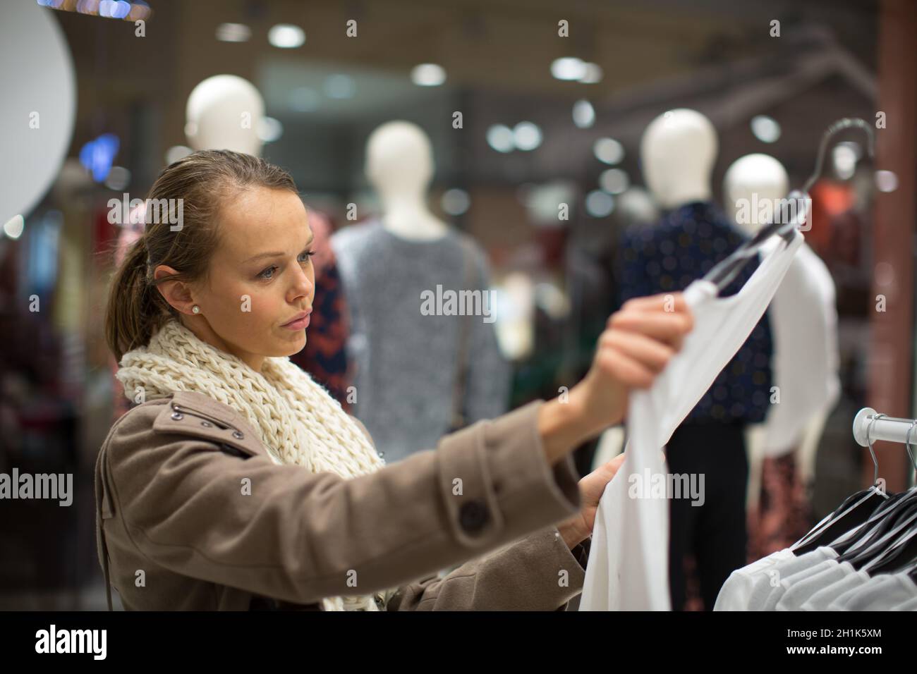 Jeune femme shopping dans un magasin de mode (tons de couleur peu profondes ; image DOF) Banque D'Images