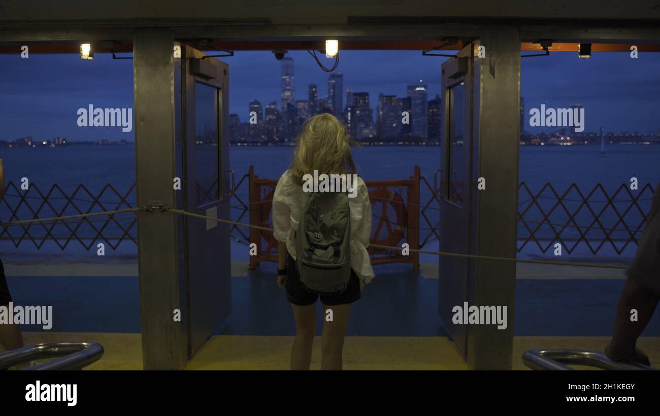 Une femme regarde au loin, en pensant profondément tout en regardant les gratte-ciel de la ville de New York tout en empruntant le ferry de Staten Island.Vue arrière de à Banque D'Images