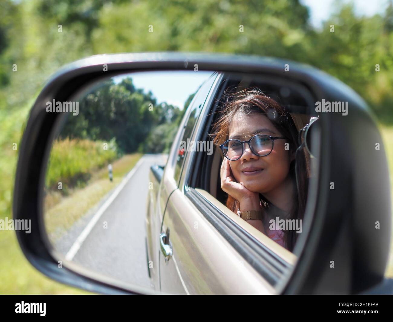 Un miroir de vision latérale pour femme qui regarde hors de la voiture en conduisant une voiture. Banque D'Images