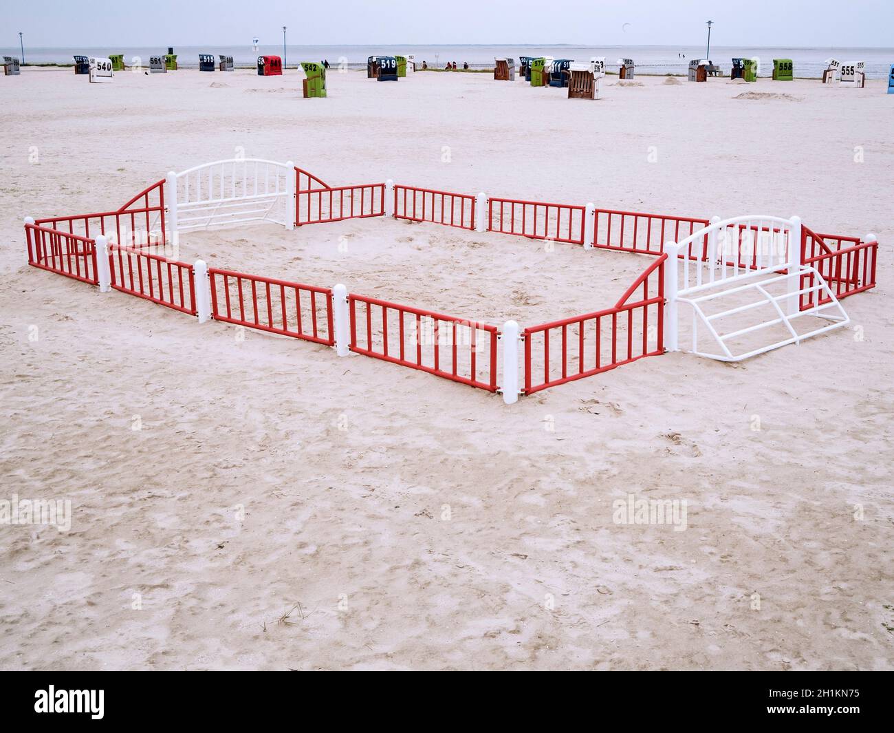 Paysage de plage allemand de la mer du Nord avec un petit terrain de jeu de boules de plage clôturé en premier plan et des chaises de plage en osier numérotées loin derrière avec un Banque D'Images