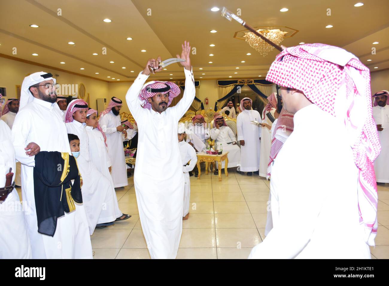 2020 juillet, salle de mariage Riyad, Arabie Saoudite, hommes saoudiens célébrant et appréciant la danse traditionnelle avec des objets culturels entre les mains pendant l'événement de mariage Banque D'Images