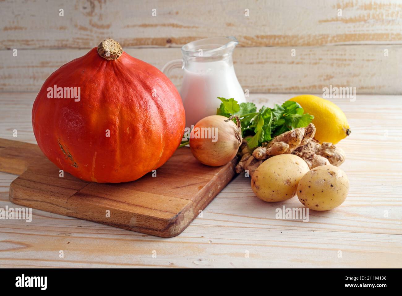 Courge kuri rouge et ingrédients pour une soupe d'automne végétalienne avec du lait de coco, du gingembre et de la coriandre pour Thanksgiving et Halloween sur une table en bois, copie Banque D'Images