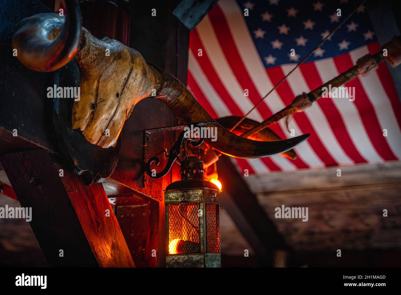Crâne de buffle vieilli grundy, lampes rétro et arc sur le drapeau américain flou en arrière-plan. Halloween concept, fond ou texture dans le style occidental Banque D'Images