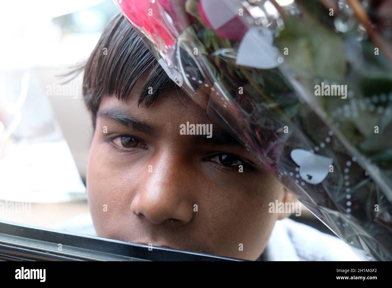 Un pauvre garçon essayant de vendre des fleurs dans la rue de Delhi, en Inde Banque D'Images