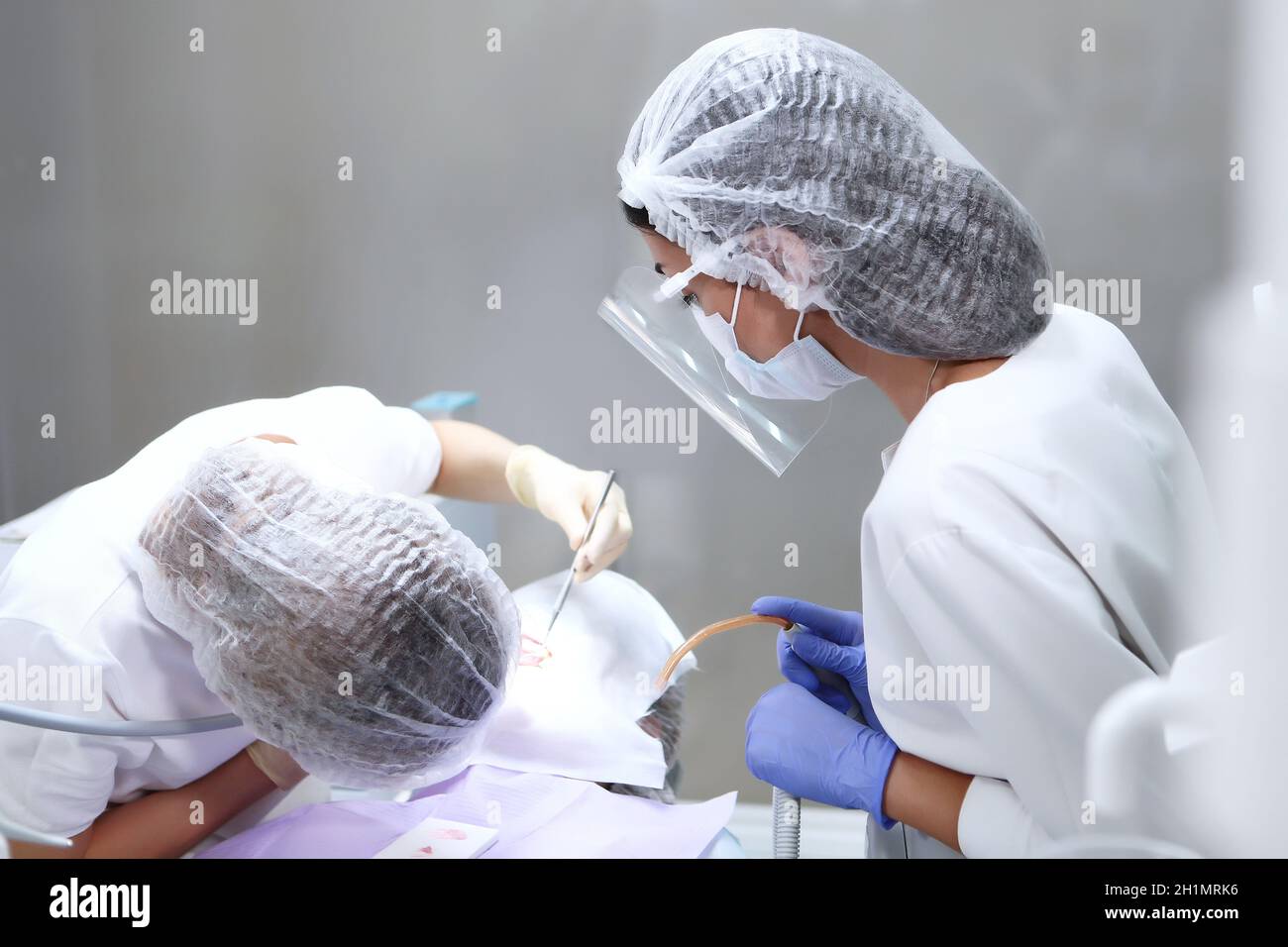 Le dentiste et l'assistant effectuent un nettoyage dentaire professionnel pour le patient.Écran de protection et masque médical sur le visage.Le concept de santé. Banque D'Images Le dentiste et l'assistant effectuent un nettoyage dentaire professionnel pour le patient.Écran de protection et masque médical sur le visage.Le concept de santé. Banque D'Images