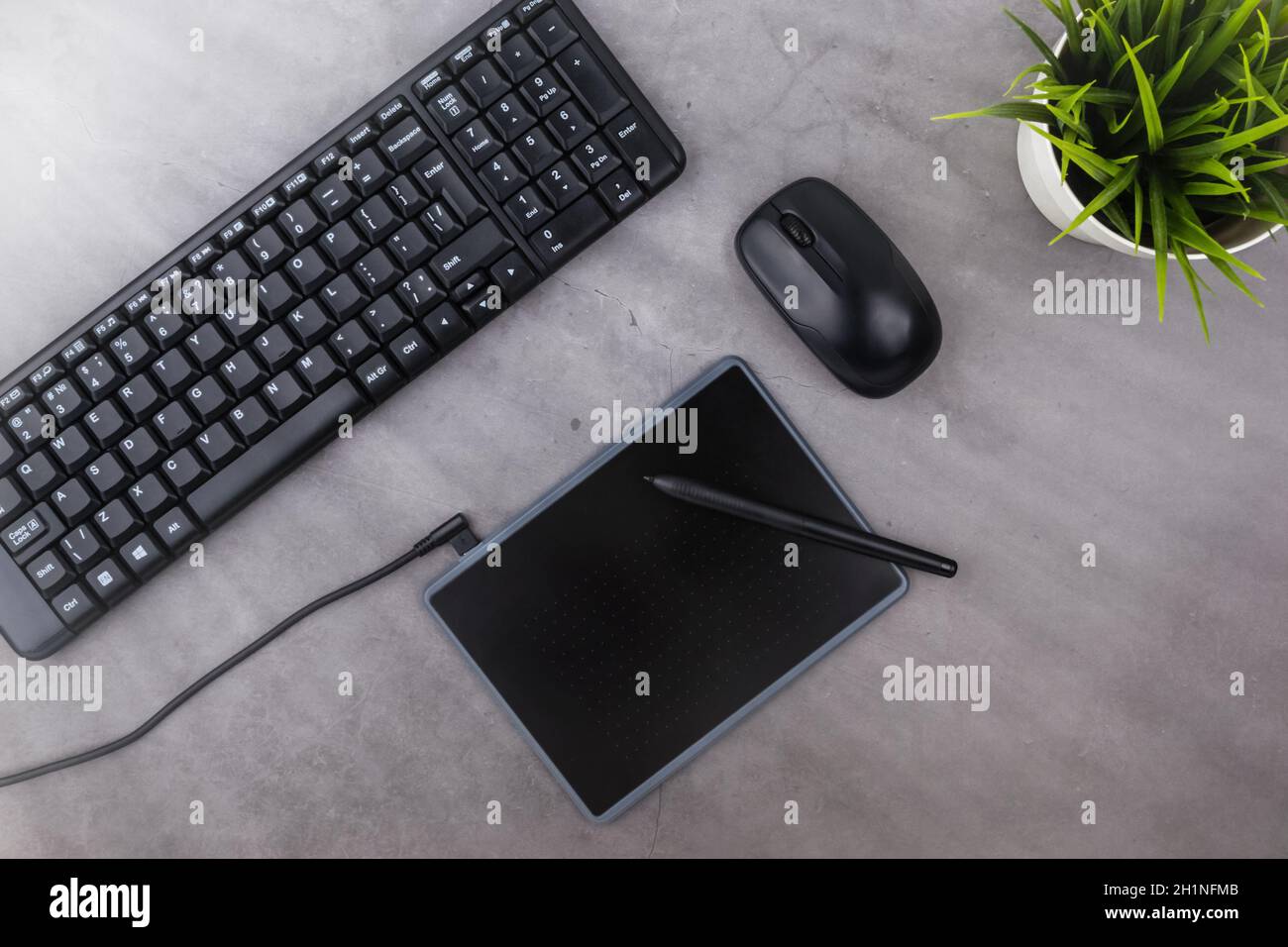 Lieu de travail sur table avec copie espace sombre. Clavier, souris, stylo, tablette graphique, fleur en pot. Mise à plat. Vue de dessus, les rayons de soleil de th Banque D'Images