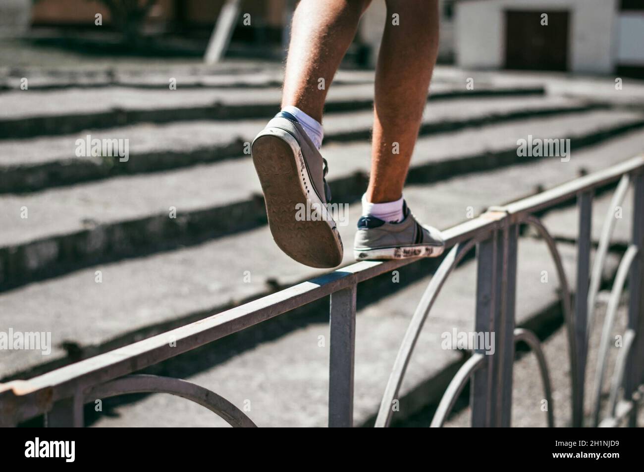 Le gars des baskets marche sur la clôture. Montez au-dessus de la clôture. Banque D'Images