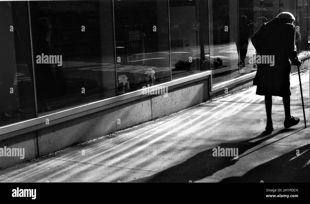 une vieille femme qui se rentrent à la maison seule à l'aide d'une canne Banque D'Images