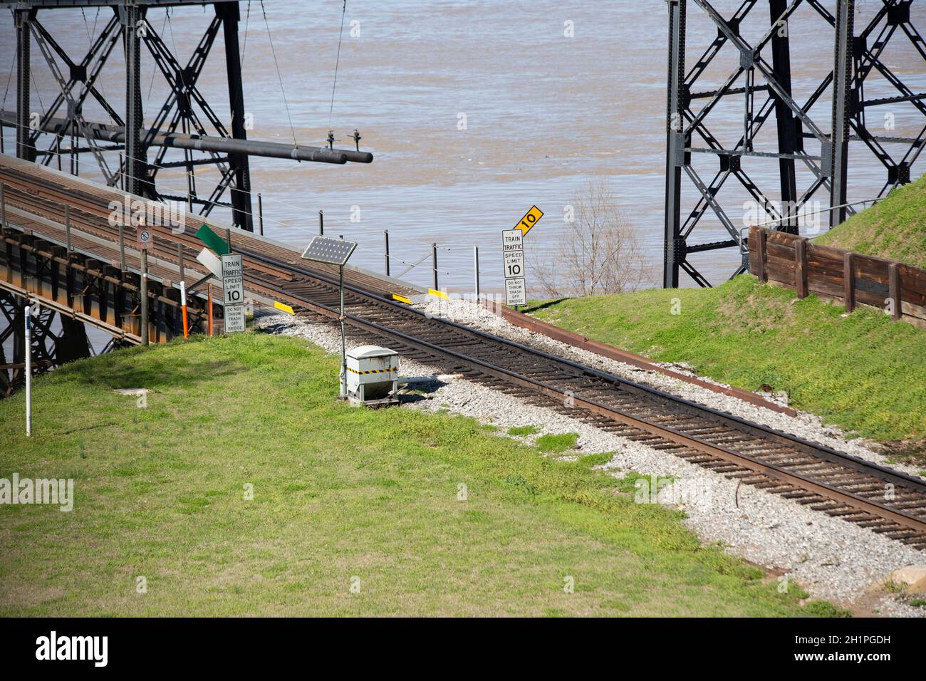 Voies ferrées traversant une rivière, panneaux indiquant « trafic ferroviaire », « limite de vitesse de 10 miles à l'heure » et « ne pas jeter de déchets sur le pont » Banque D'Images