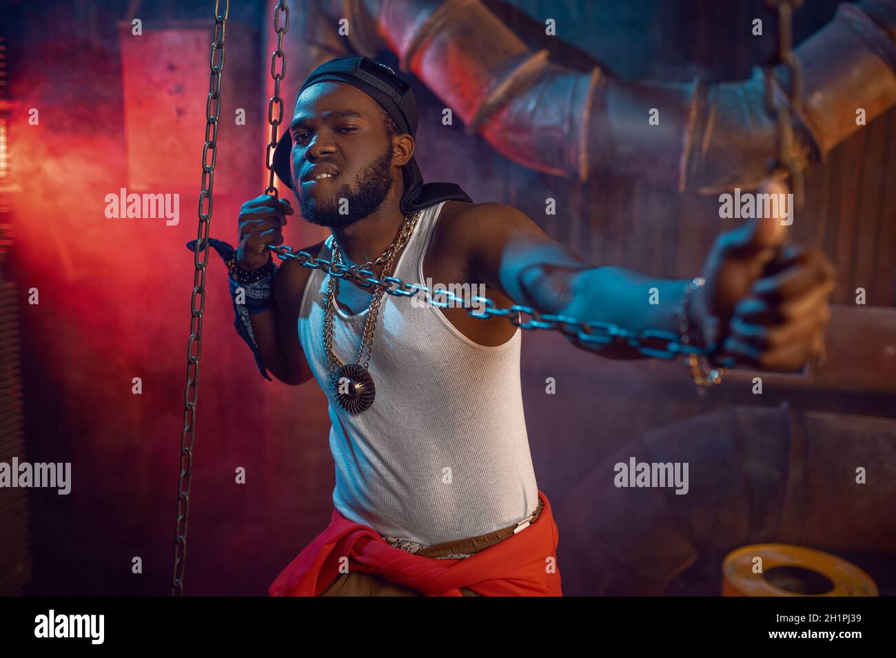 Pose de rapper élégante avec chaînes en studio avec décoration souterraine fraîche.Hip-hop, chanteur de rap, break-dance Banque D'Images