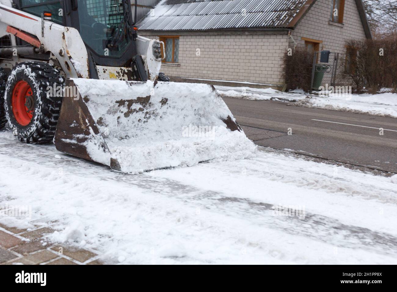 Petite pelle bobcat travaillent dans la rue, la neige nettoyage Banque D'Images