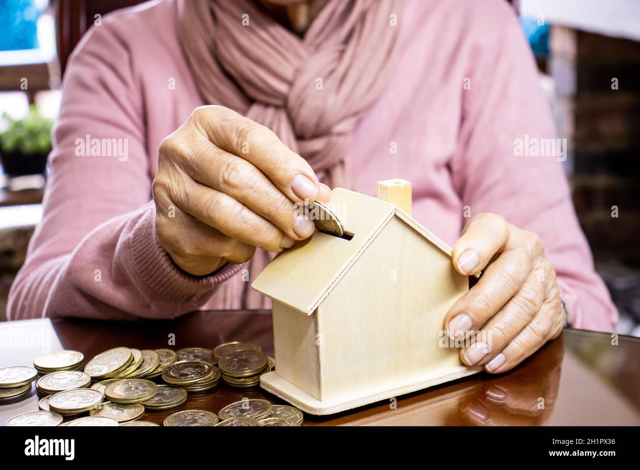 Gros plan d'une main d'une femme sénior sa maison économisant de l'argent Banque D'Images