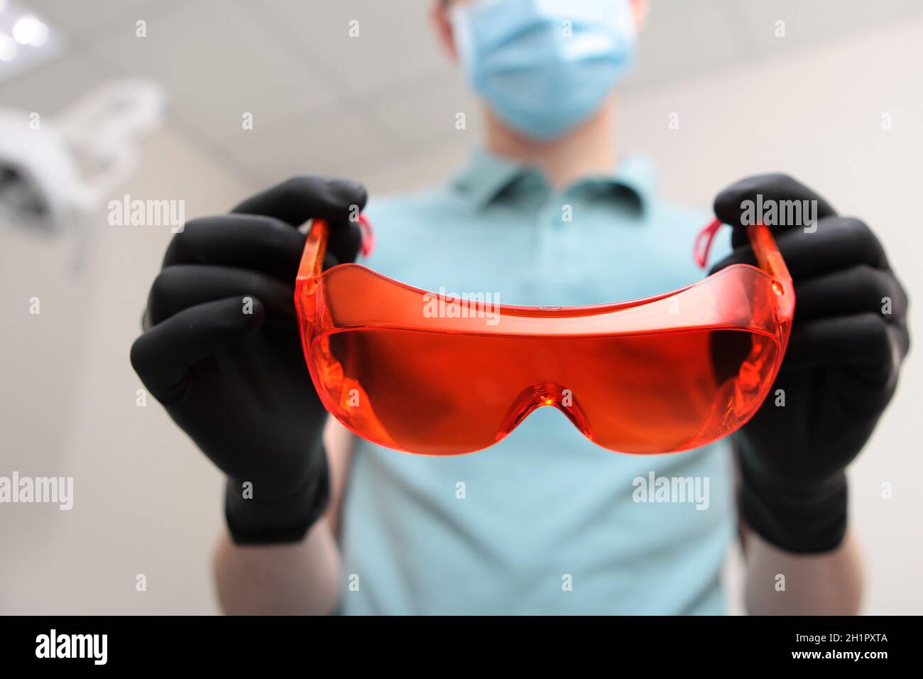 Le médecin dentiste porte des gants et porte des lunettes de sécurité de couleur orange.Photo non reconnaissable.Copier l'espace. Banque D'Images