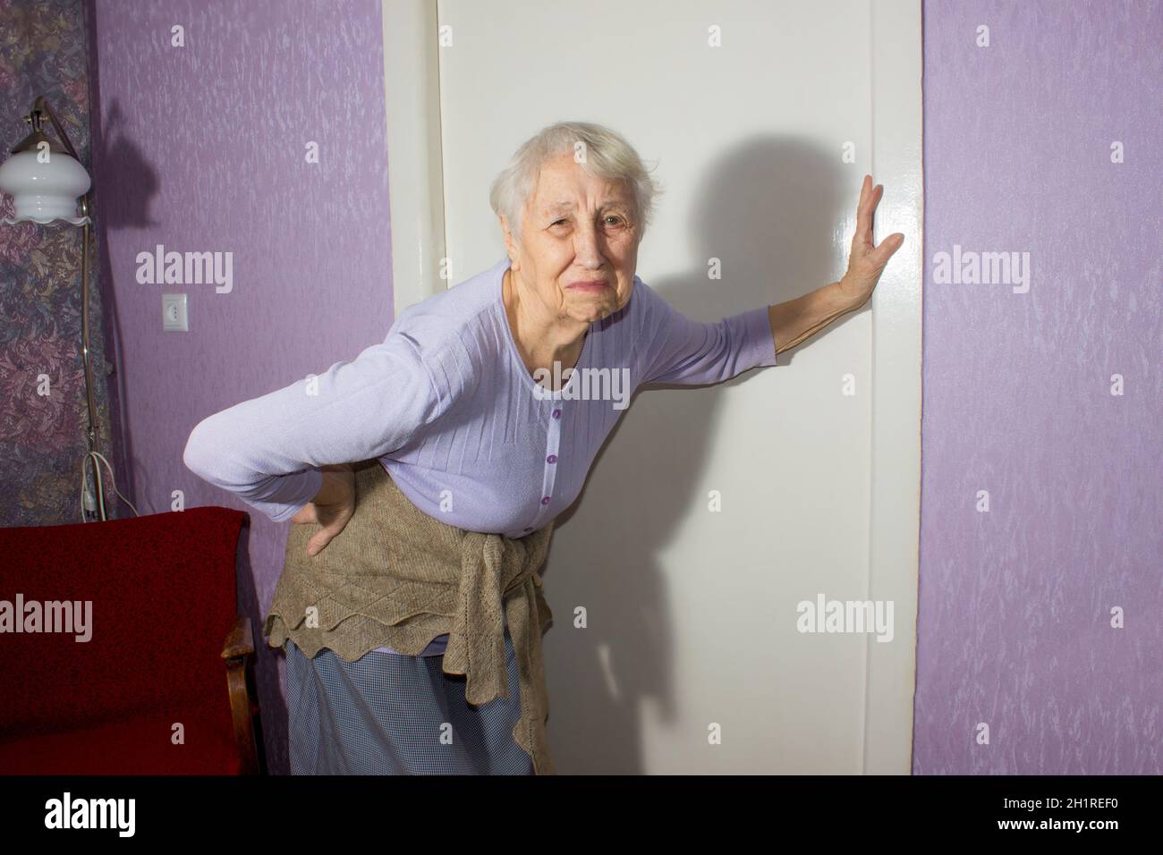 Femme âgée de 75s avec des sentiments douloureux massant bas de dos pour réduire la douleur, mal de dos inconfort.Maladies des personnes âgées, lésion du nerf sciatique Banque D'Images