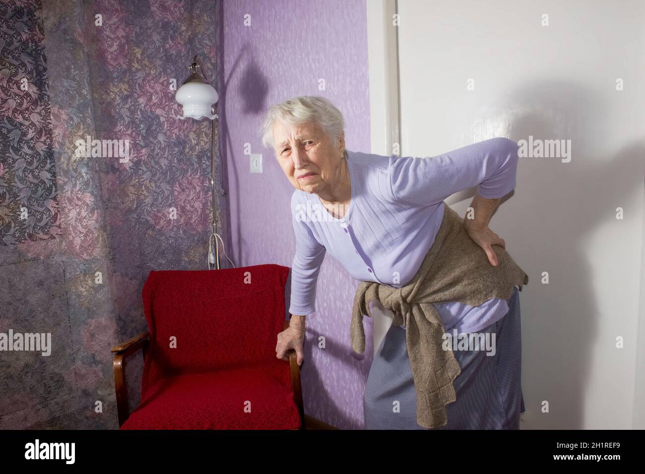 Femme âgée de 75s avec des sentiments douloureux massant bas de dos pour réduire la douleur, mal de dos inconfort.Maladies des personnes âgées, lésion du nerf sciatique Banque D'Images