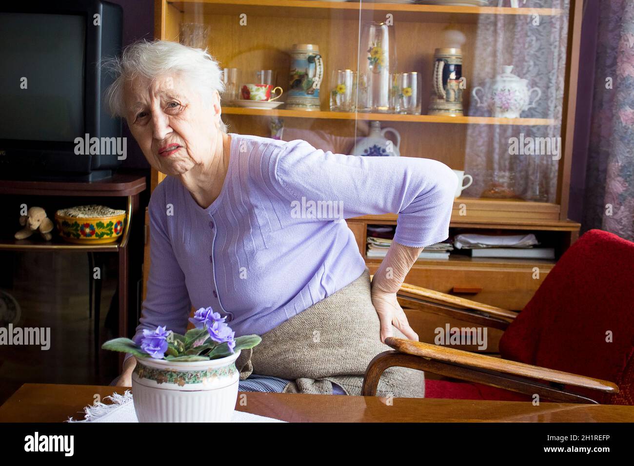 Femme âgée de 75s avec des sentiments douloureux massant bas de dos pour réduire la douleur, mal de dos inconfort.Maladies des personnes âgées, lésion du nerf sciatique Banque D'Images