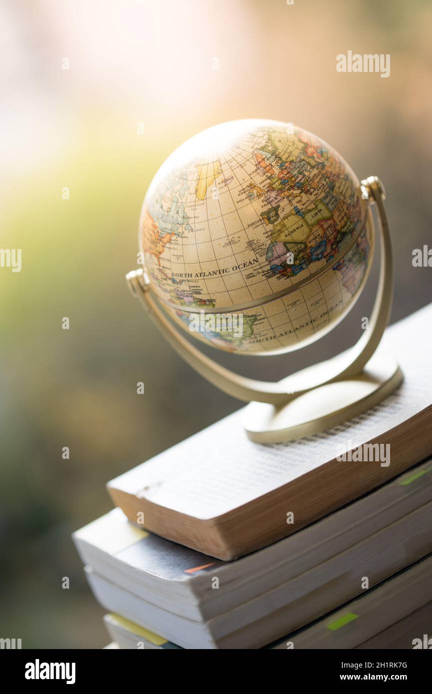 Modèle miniature globe debout sur une pile de livres. Symbole pour voyager. Banque D'Images