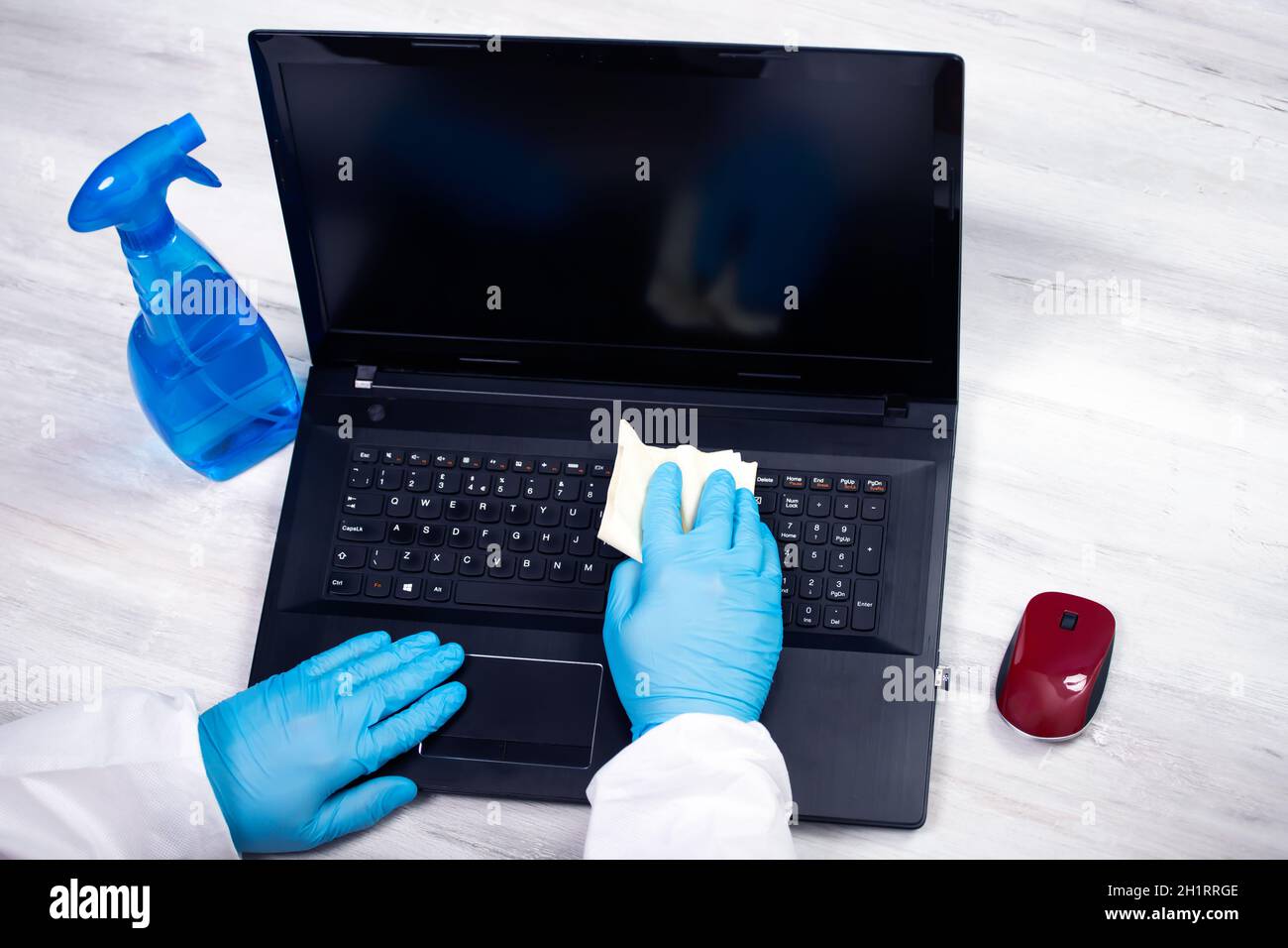 Désinfection de bureau essuyant ordinateur portable avec désinfectant. Coronavirus COVID-19 assainir, désinfecter le bureau de travail. Banque D'Images